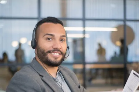 Smiling customer service representative wearing headset holding document in modern office setting