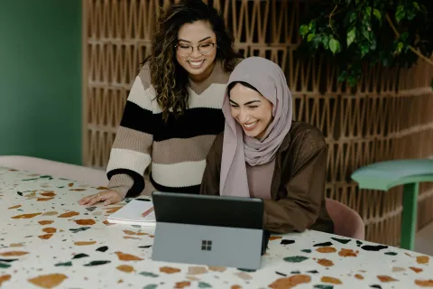a couple of women sitting at a table with a laptop