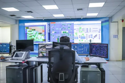 Man monitoring multiple control system screens in a modern control room with digital interfaces and data displays
