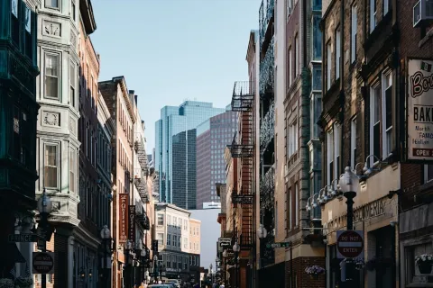 Urban street view with historic brick buildings and modern skyscrapers in background under clear sky.