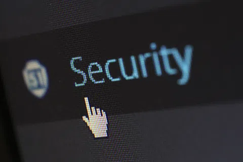 Cursor pointing at the word Security on a digital screen with a shield icon, emphasizing online protection