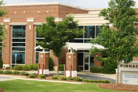 Exterior view of Pinnacle Orthopaedics and Sports Medicine brick building with trees and signage