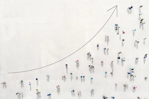 Aerial view of people walking along an upward trending arrow symbolizing growth and progress.