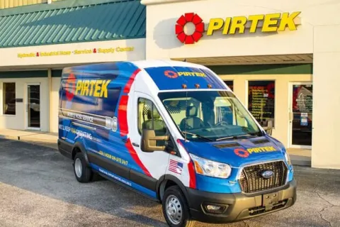 Pirtek service van parked outside a Pirtek hydraulic and industrial hose service center building.