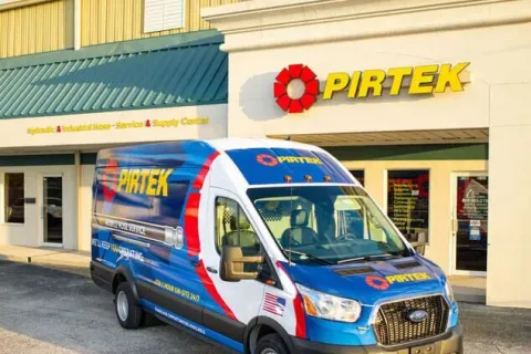 Pirtek service van parked outside a Pirtek hydraulic and industrial hose service center building.