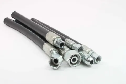 Set of black hydraulic hoses with silver metal fittings on white background