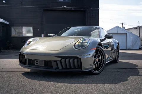 Sleek gray Porsche sports car parked outdoors with a modern design and polished finish under daylight.