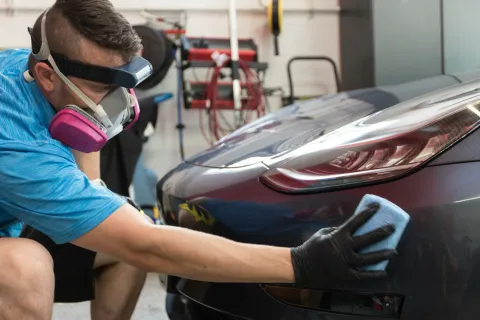a person wearing a mask and gloves working on a car