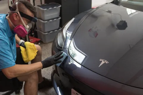 a person wearing a mask and gloves working on a car
