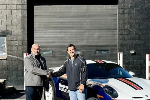 two men standing next to a car