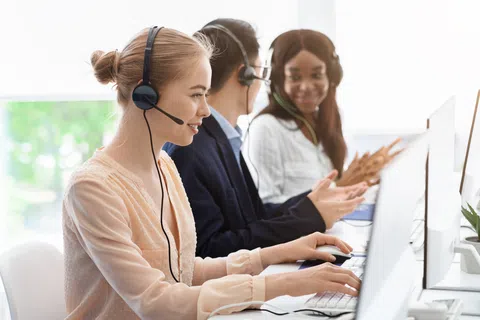 Customer support team working with headsets and computers in a bright office environment