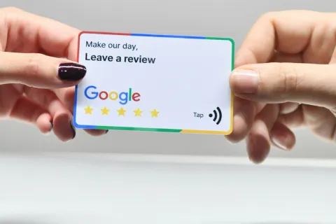 Two hands holding a Google review card asking to leave a 5-star review with an Apple logo in background.