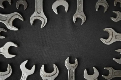 A circular arrangement of various metallic wrenches on a dark surface.
