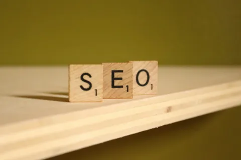 Wooden tiles spelling out SEO on a shelf with a green background.