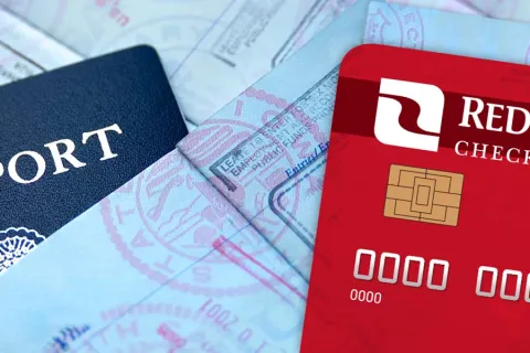 A close-up of a passport and a red credit card placed on top of travel documents, symbolizing travel finance.
