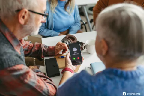 Senior couple looking at smartphone showing an incoming call from an unknown caller during a meeting.