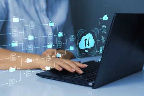 Person using laptop with digital cloud storage and file management icons floating above keyboard