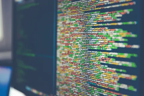 Close-up of colorful computer programming code displayed on a monitor screen with a blurred background.
