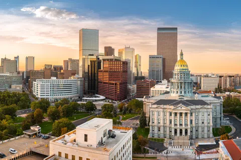 Denver city skyline with the Colorado State Capitol and skyscrapers at sunrise under a clear sky