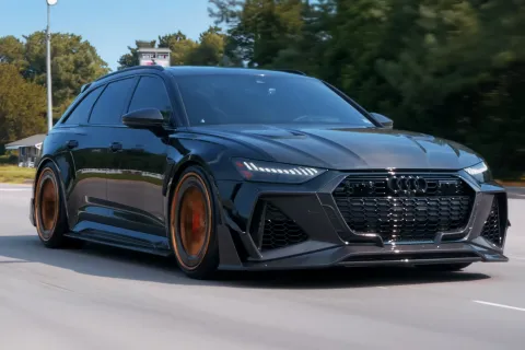 Green Audi RS6 Avant driving on road with custom bronze wheels and aggressive front grille under daylight.