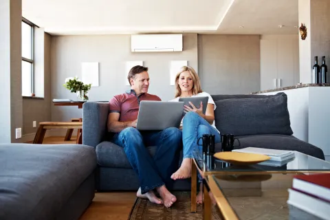 a man and a woman sitting on a couch with a laptop