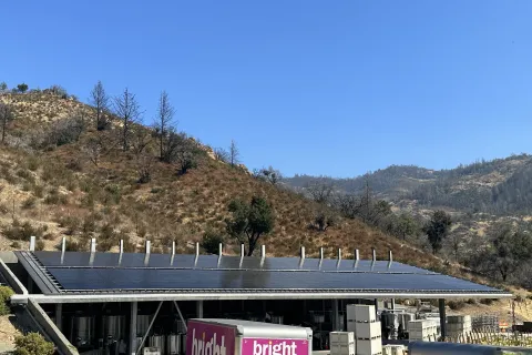 a building with a roof and a hill in the background