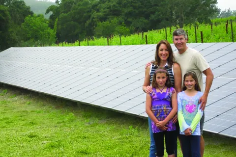 a group of people posing for a photo in front of a solar panel