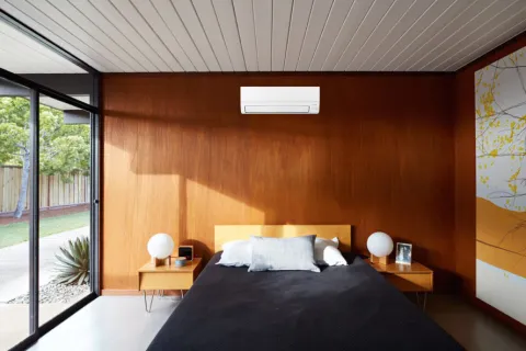 Modern bedroom with wooden wall, bed, and air conditioning unit on display, showcasing a stylish interior design.