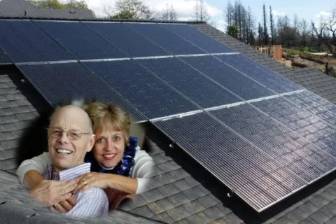 a man and woman standing in front of solar panels