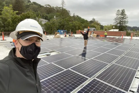 a man wearing a hard hat and standing on a solar panel