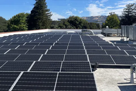 A rooftop covered with solar panels under a clear blue sky, showcasing renewable energy solutions.