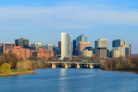 Calm river with bridge and modern city skyline under clear blue sky during daytime