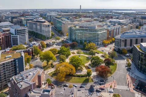 Aerial view of Washington DC showing a circular park surrounded by buildings with the Washington Monument in the background.