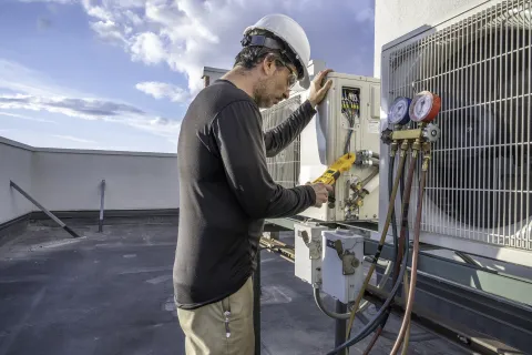 man in hard hat tunes hvac for repair