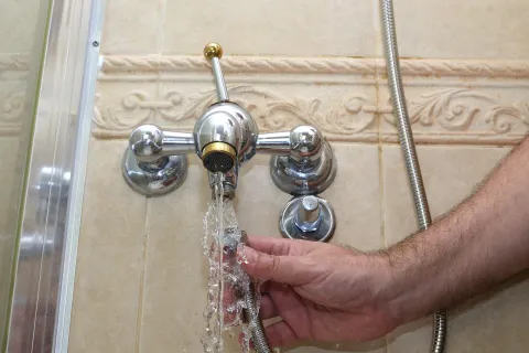 a hand holding a metal faucet