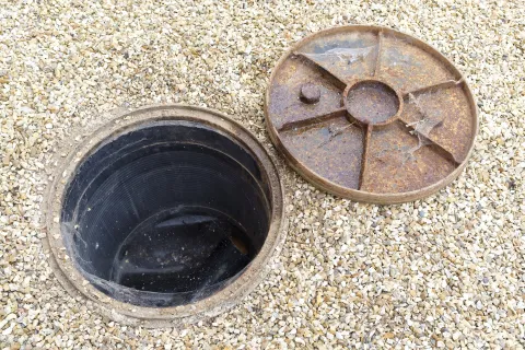 open sewer cap in gravel ground