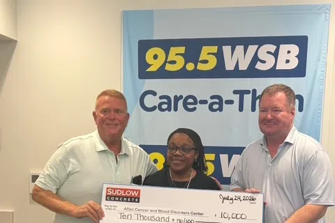 Three people holding a large $10,000 donation check during the 95.5 WSB Care-a-Thon event.