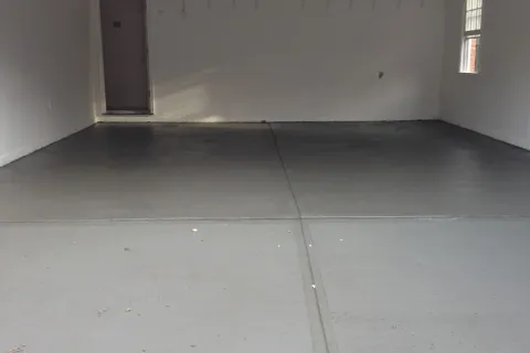 Clean and empty garage with painted concrete floor and minimal wall hooks.