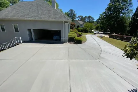 Newly poured clean concrete driveway leading to a residential garage on a sunny day.