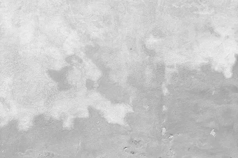 Textured concrete wall surface with light gray and white patches and rough uneven patterns.