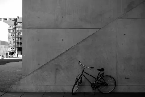 a bicycle parked next to a concrete wall