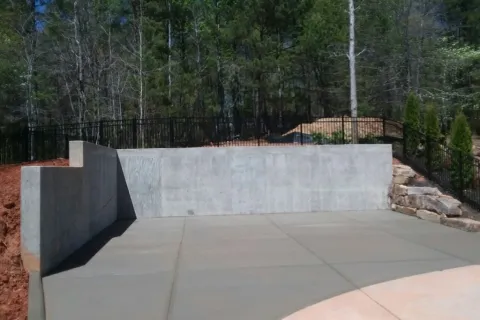 a concrete wall with a fence and trees in the background