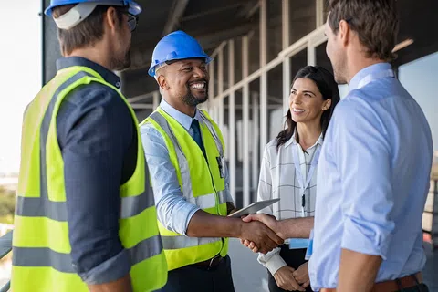 Construction workers and business people shaking hands.