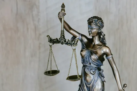 Bronze statue of Lady Justice blindfolded holding balanced scales and sword symbolizing law and fairness.