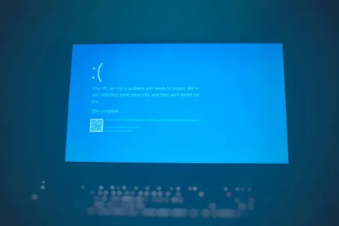 Windows PC blue screen error with sad face indicating system crash and restart in progress