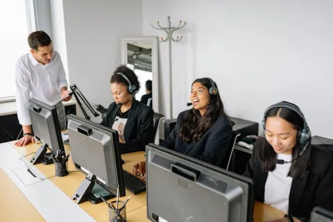 Customer support team wearing headsets working at computers in a modern office environment