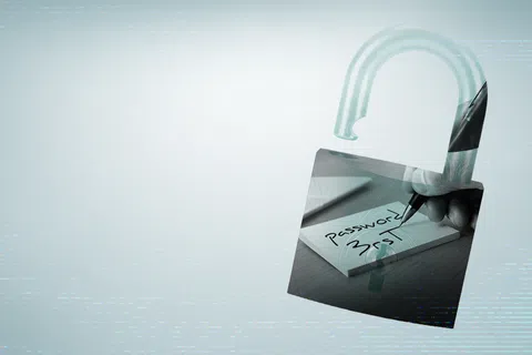Open padlock overlaid with image of hand writing password on paper, symbolizing password security risk.