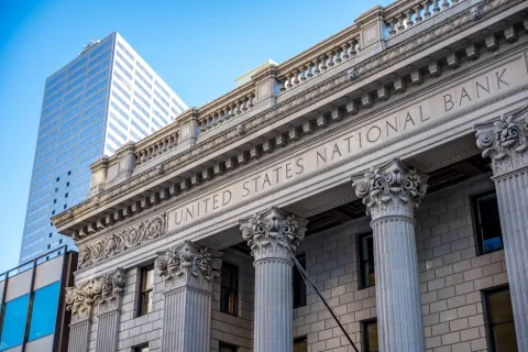 Facade of the United States National Bank building with ornate columns and clear blue sky
