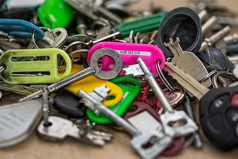 Close-up of assorted keys and colorful plastic key tags on a messy surface