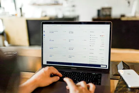 Person working on MacBook Pro displaying financial dashboard with accounting charts in accordance with the FTC compliance and cyber insurance.